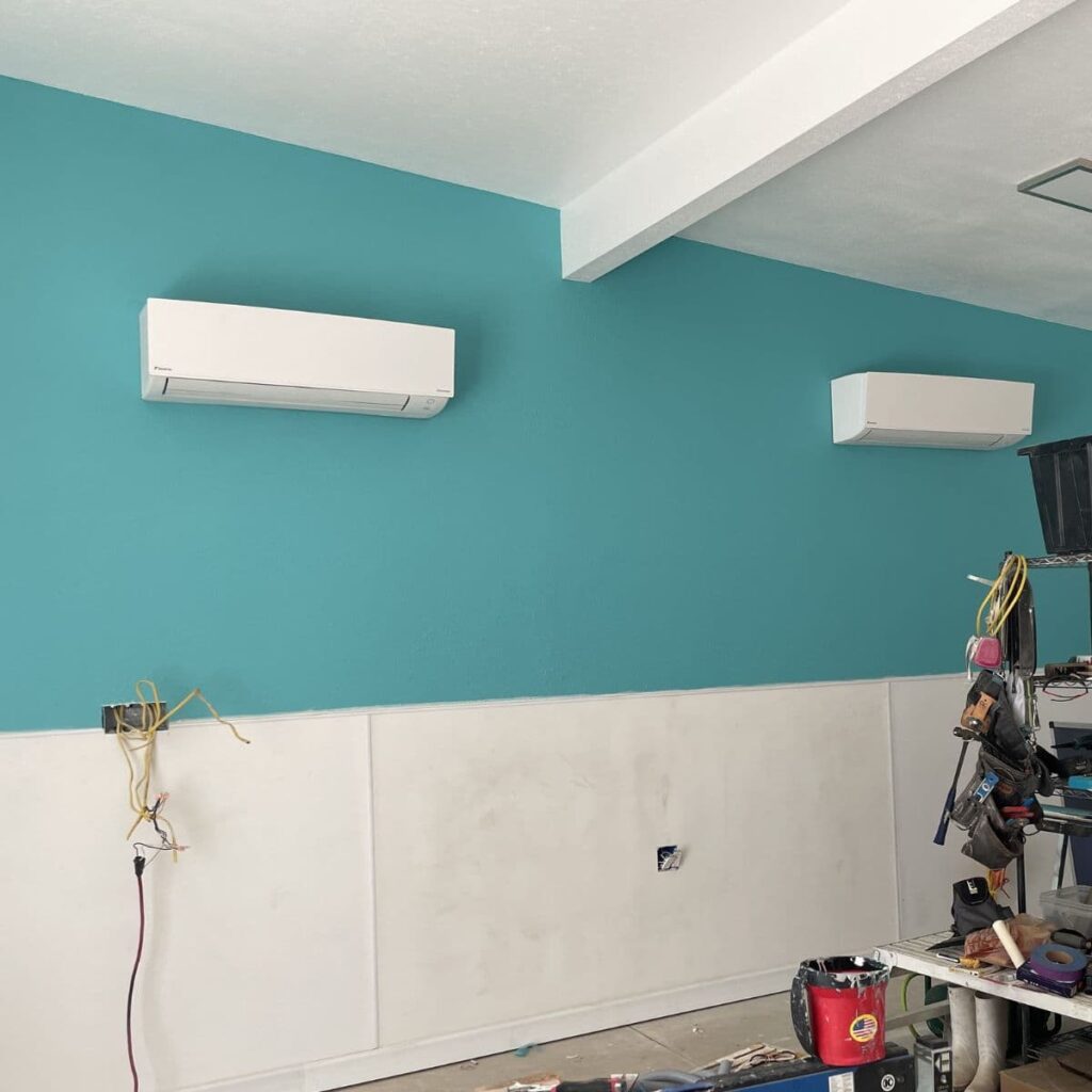 closeup of two ductless ac units positioned on a blue wall with a white ceiling