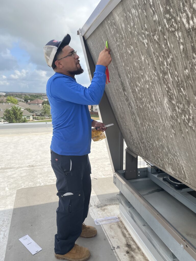 e+m emergency air conditioning technician performing maintenance on a commercial unit