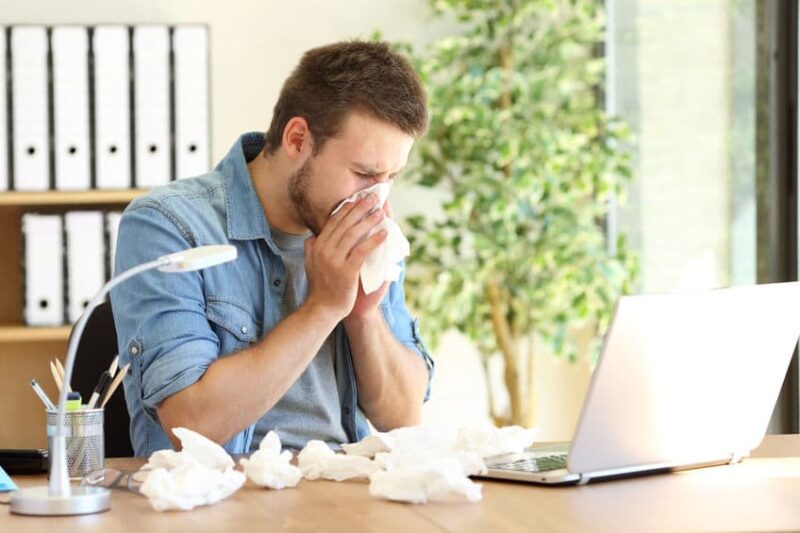 man sneezing into tissue because of poor indoor air quality
